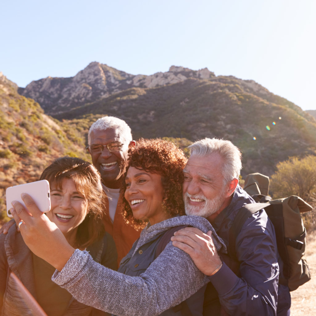 Group Of Senior Friends Posing For Selfie As They Hike Along Trail In Countryside Together